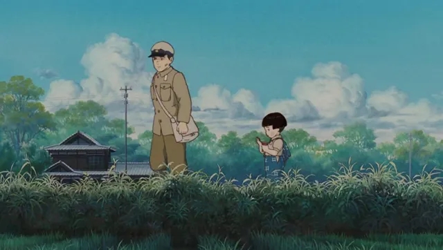 Seita and his younger sister Setsuko walk through a lush, grassy field under a cloudy sky in Grave of the Fireflies.
