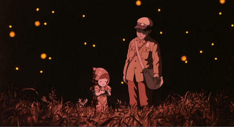 Seita and his younger sister Setsuko stand in a field of fireflies at night in the anime movie Grave of the Fireflies.