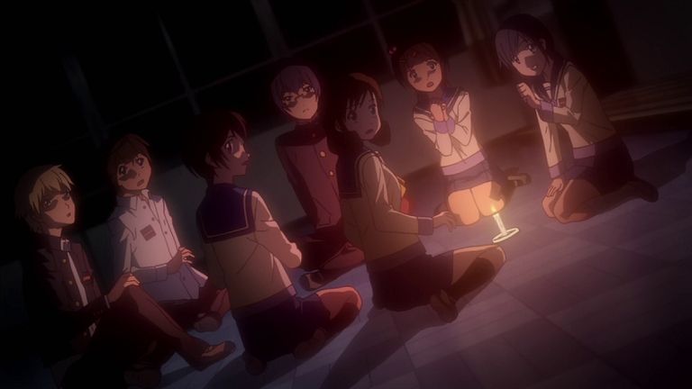 Students gather around a candle in a dark room at the beginning of the ritual
